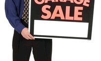 man holding garage sale sign