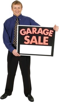 man holding garage sale sign