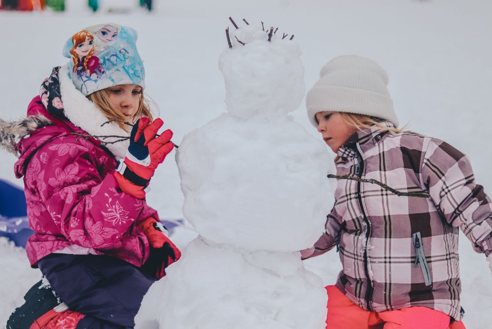 two girls building a snowman